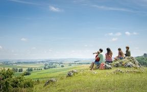 Familie sitzt auf einem Felsen und blickt auf die Landschaft.