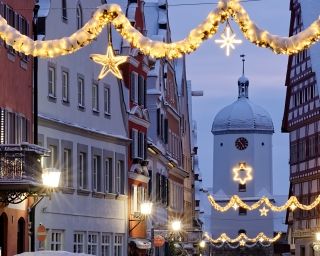 Schneebedeckte Straße mit festlicher Beleuchtung und historischem Gebäude.