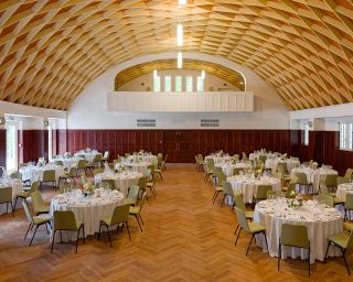 Geräumiger Saal mit runden Tischen und eleganter Dekoration.