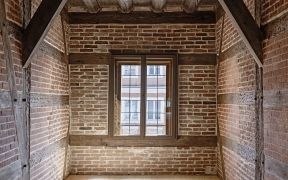 Innenansicht eines Raumes mit Ziegelwänden und Holzfenster.