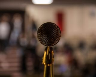 Mikrofon im Vordergrund mit verschwommenem Hintergrund.